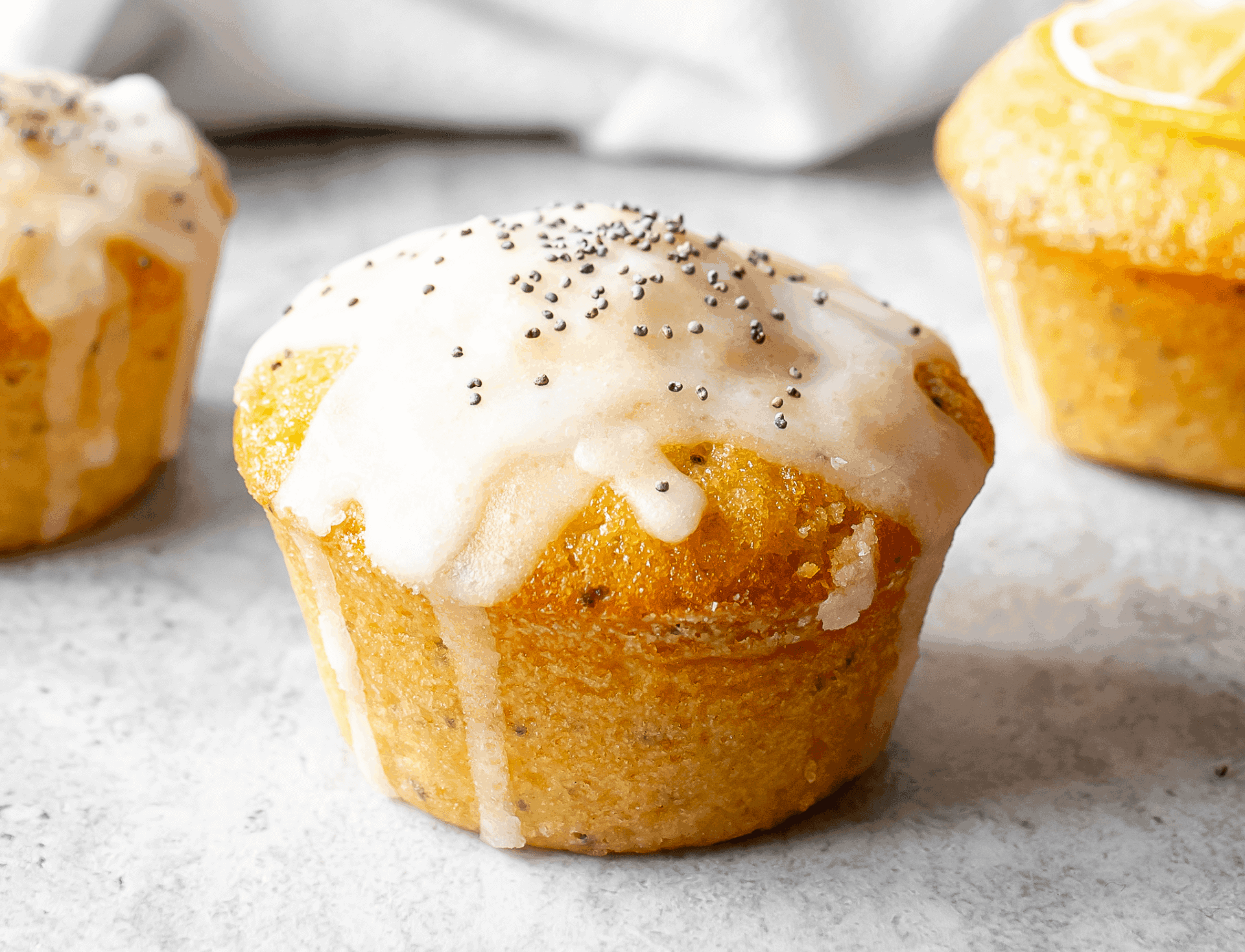 Muffin topped with glaze and poppyseeds.