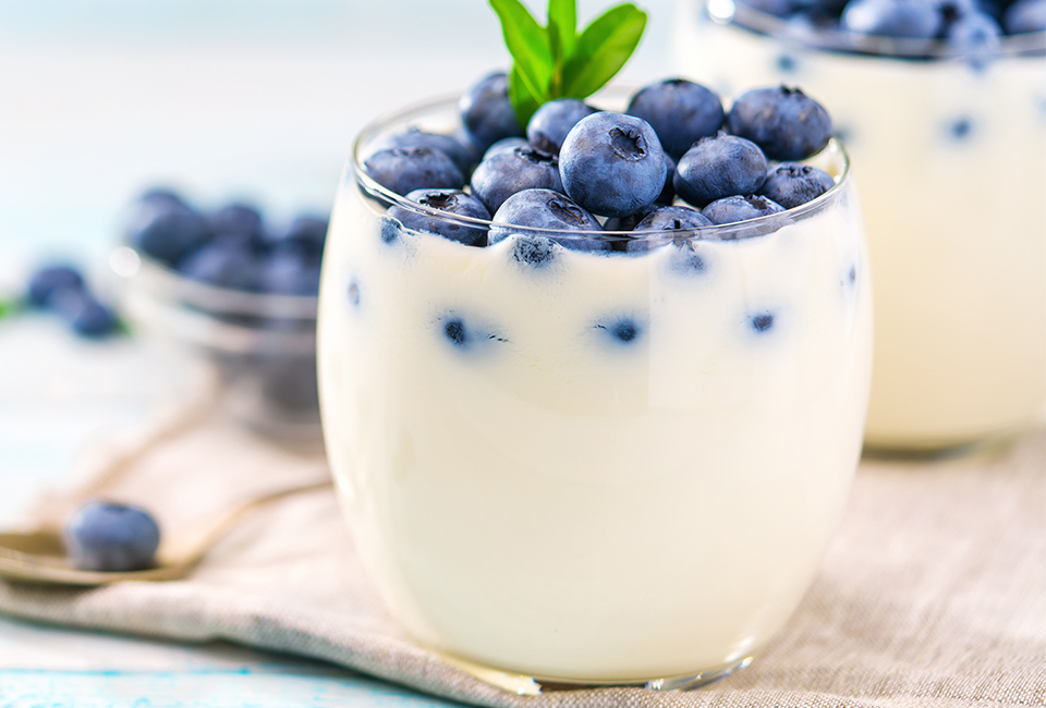 White yogurt in clear container topped with blueberries and mint.