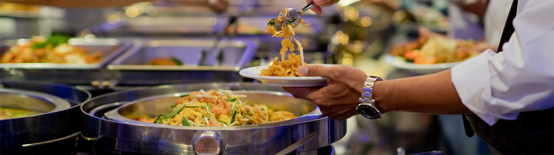 person serving pasta at a buffet