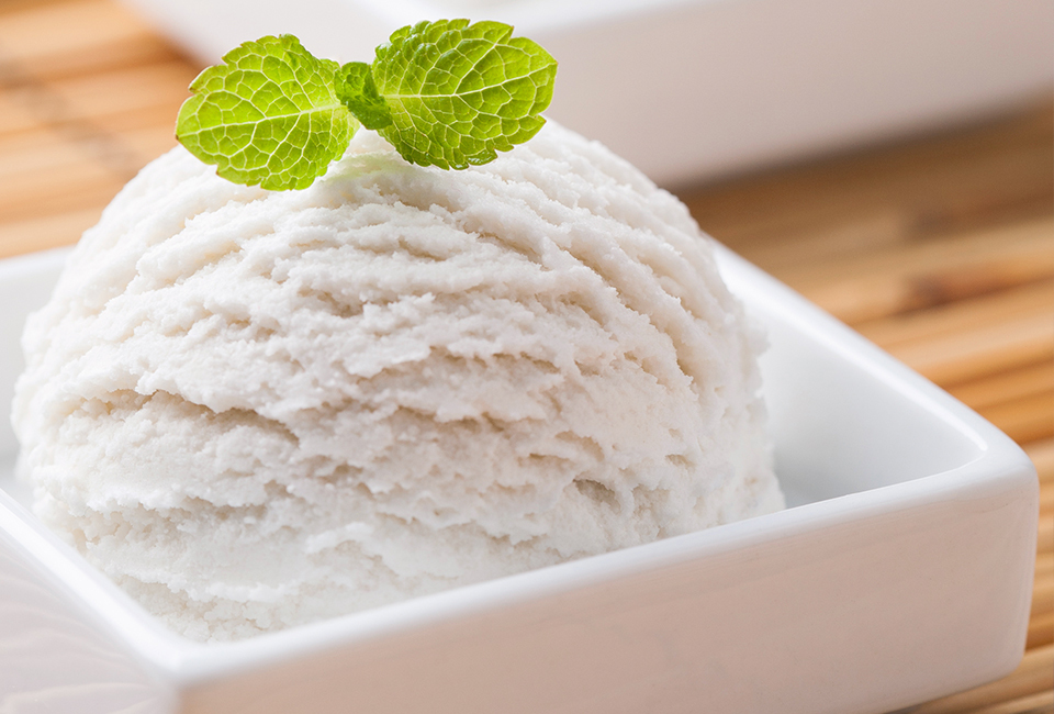 Scoop of ice cream in square dish topped with mint.