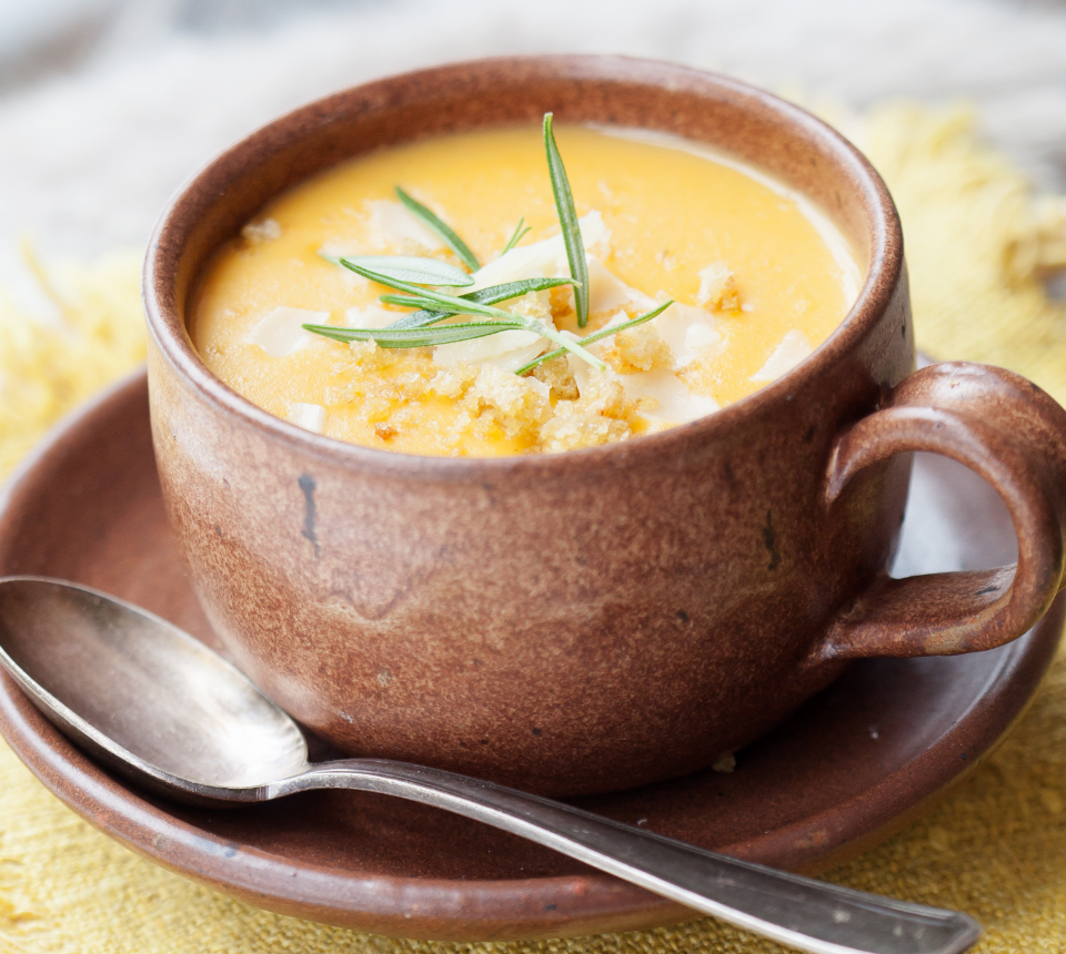 Brown mug of orange bisque topped with herbs.