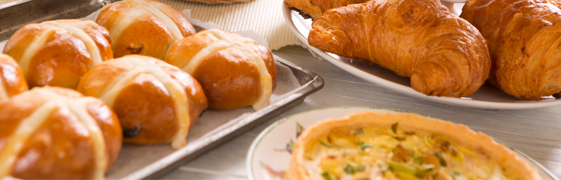 Various baked goods: buns, quiche and croissants.