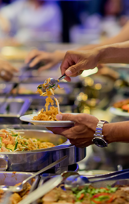 person serving a plate from a buffet line