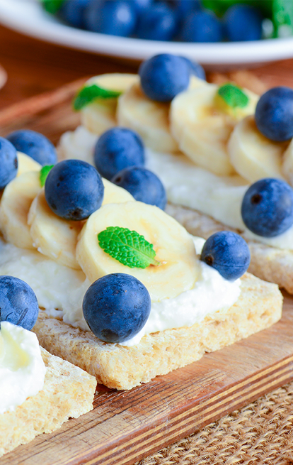 wafers with cheese spread topped with bananas and blueberries